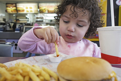 A young girl eats some fries.