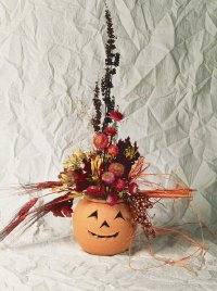 This Halloween decoration combines a terra cotta container with dried flowers to produce a floral jack-o'-lantern.