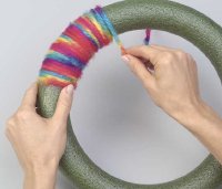 Glue the yarn to the wreath and then wrap it around.