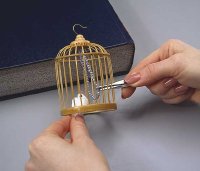 Using tweezers, glue the bird to the beaded string.