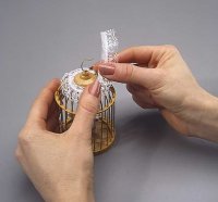 Glue strips of lace in three layers around the top of the cage.