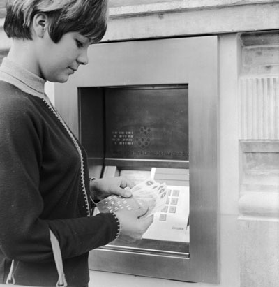 A woman withdraws money from the first cashpoint machine in London, in 1967.