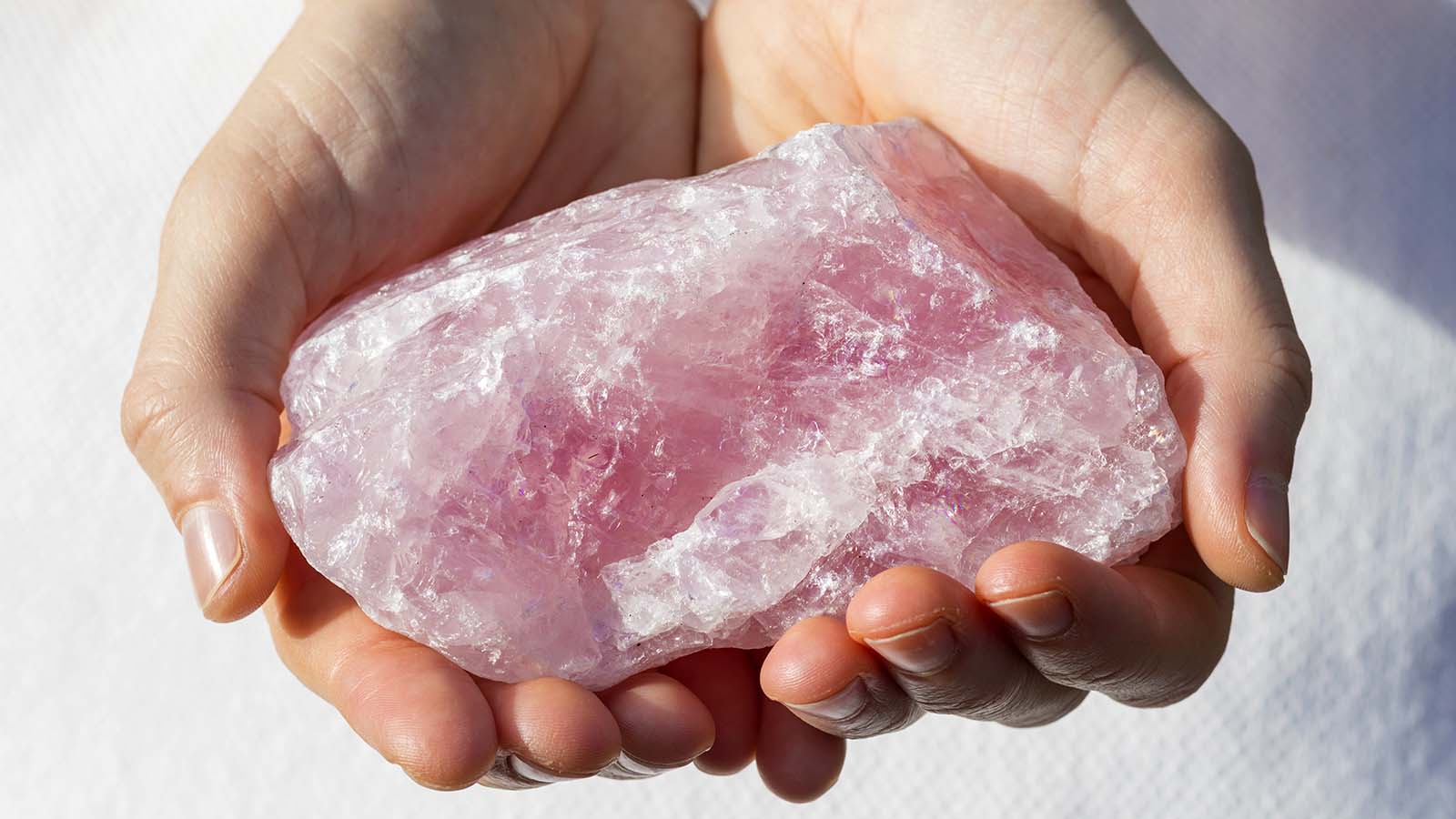  A hand holding a rose quartz crystal, symbolizing love and emotional healing, often used in meditation to open the heart chakra.
